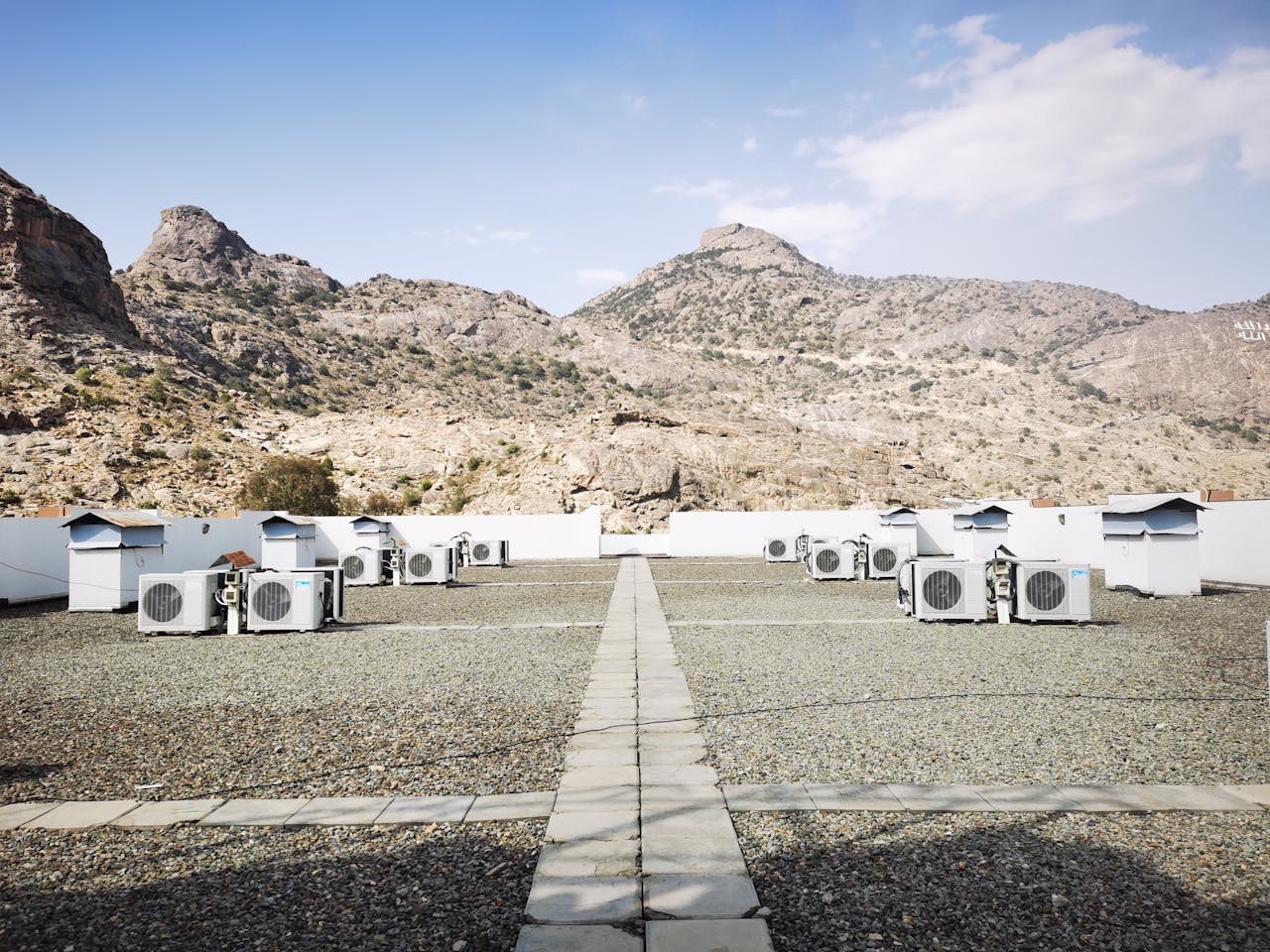 digital Rooftop air conditioning units on a gravel surface with a mountainous backdrop under a clear sky.